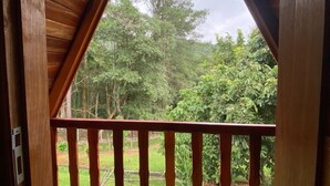Een houten balkon met uitzicht op een bebost gebied.