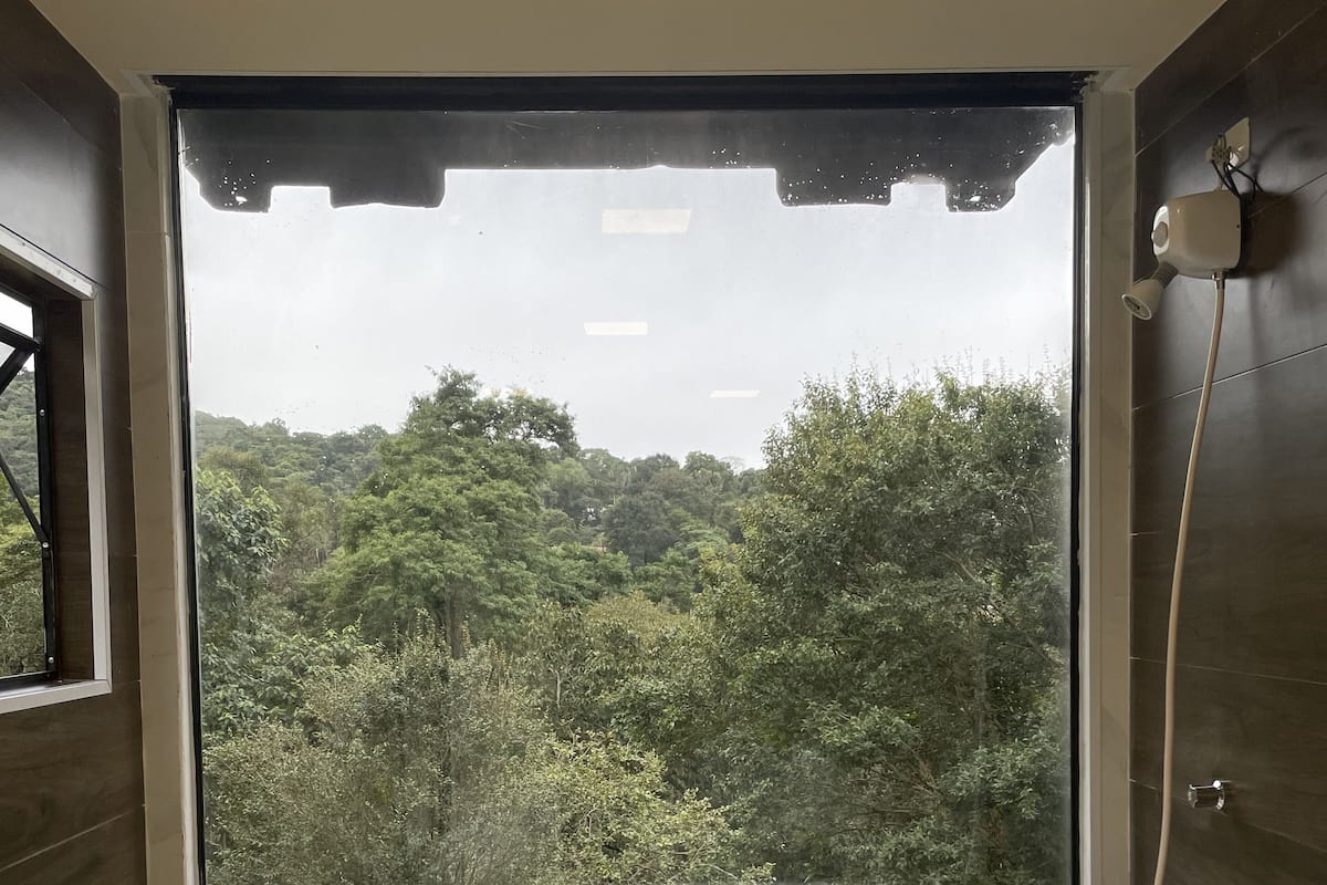 Ein Badezimmer mit großem Fenster, einer Badewanne und einer Dusche.