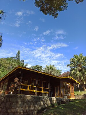 A wooden cabin with a stone foundation, large windows, and a porch area. - Pousada Belas Aguas Mairipora (Mairipora)