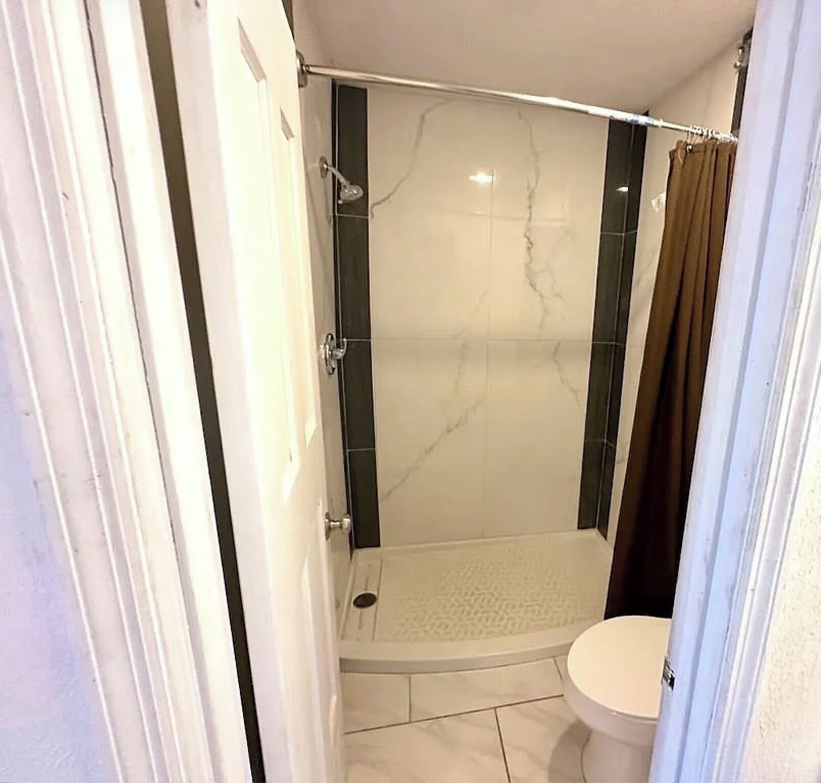 A bathroom with a glass-enclosed shower, a toilet, and a shower curtain.