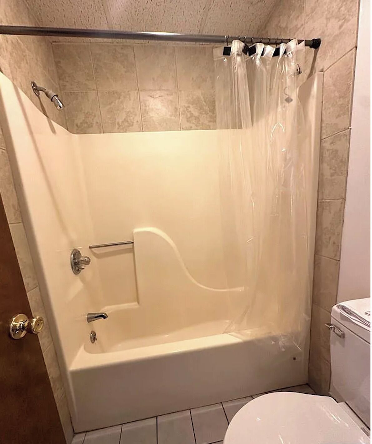 A bathroom with a bathtub, toilet, and shower curtain.