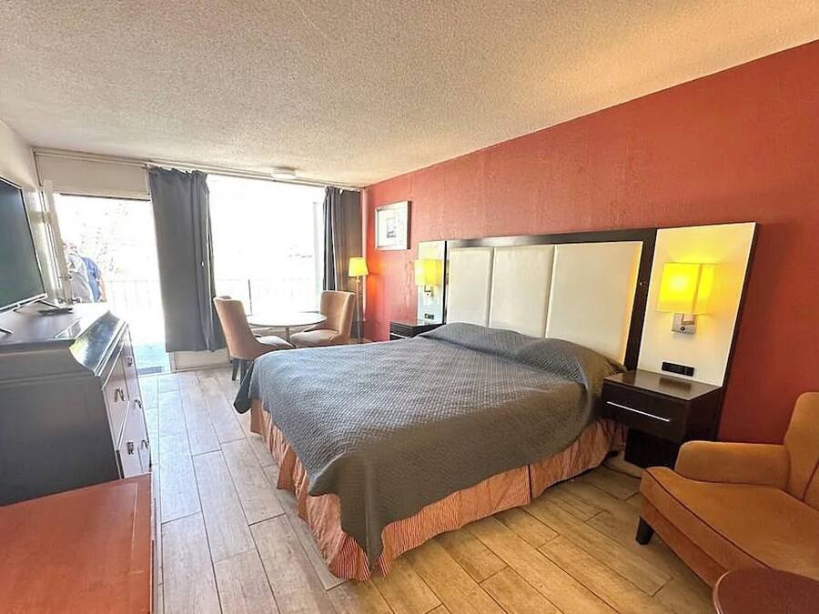 A hotel room with a large bed, a desk with a computer, a chair, and a sofa.