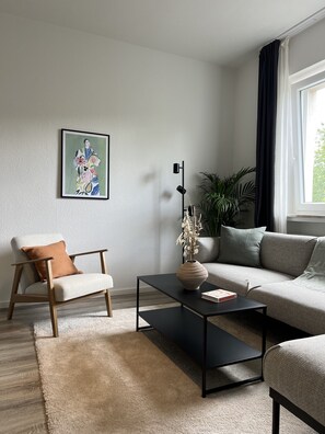 Ein stilvolles Wohnzimmer mit einer Couch, einem Sessel, einem Couchtisch und einem Bild an der Wand.