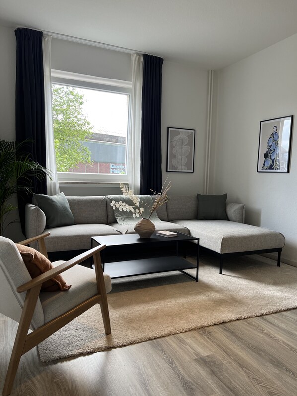 Ein modernes Wohnzimmer mit einer Couch, einem Couchtisch und einer Topfpflanze.