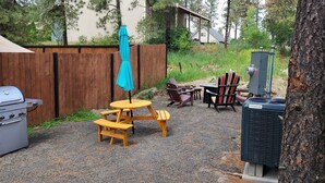 A backyard with a grill, picnic table, chairs, and a blue umbrella. - Spokane Chalet WIFI included (Spokane)