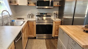 A modern kitchen with stainless steel appliances, wooden cabinets, and a herringbone-patterned rug. - Spokane Chalet WIFI included (Spokane)