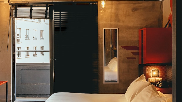 A modern hotel room with a bed, a mirror, a red cabinet, and a view of the street outside. - LOFT Hotel by Sommelier Hoteles (Santiago)