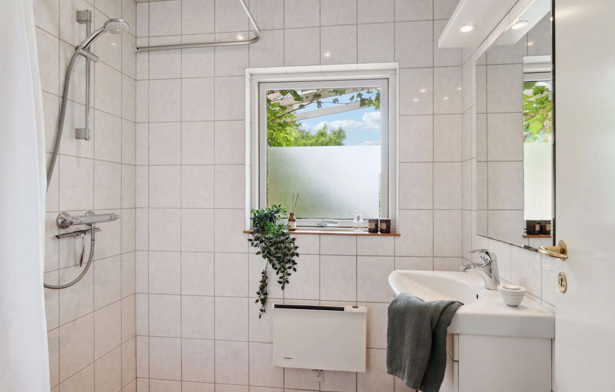 Een moderne badkamer met douche, raam met uitzicht, wastafel en spiegel.