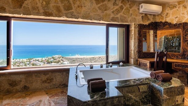 Ein Badezimmer mit einer großen Badewanne, einer Steinwand und Meerblick.