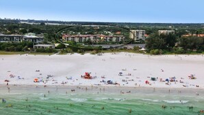 Ein Strand mit einem Hotel im Hintergrund.