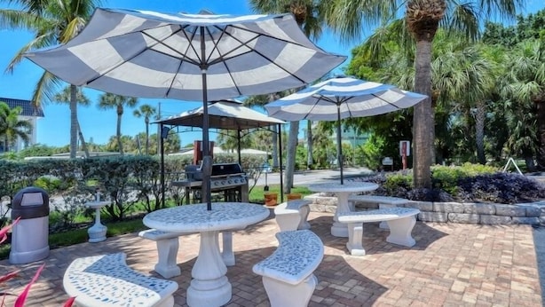 Terrasse mit Sonnenschirmen, Grill und angelegtem Garten mit Palmen.
