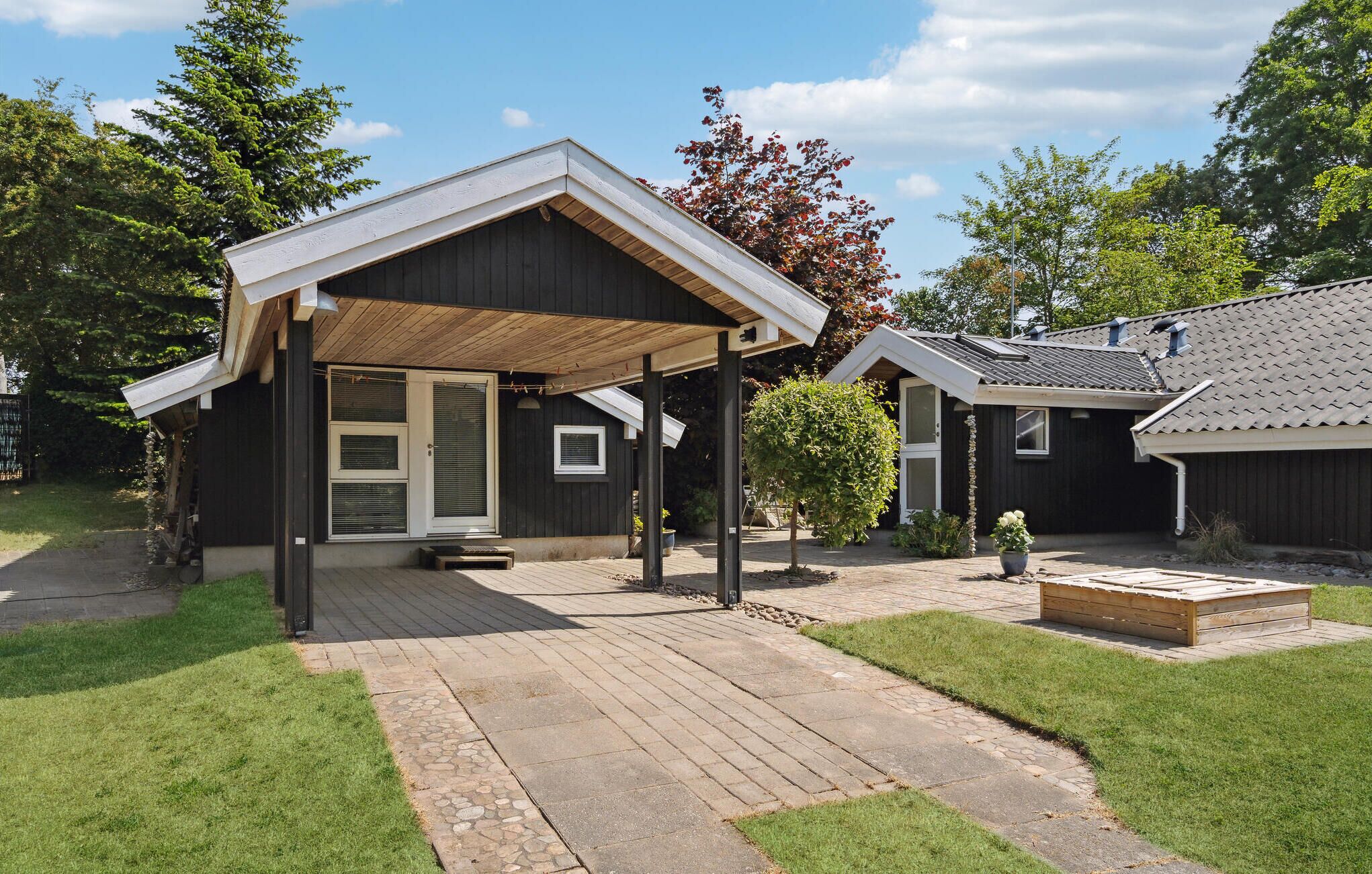 Ein zweistöckiges Haus mit überdachter Terrasse und kleinem Garten.