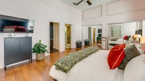 Une chambre moderne avec un grand lit, un téléviseur à écran plat, un ventilateur de plafond et une armoire.