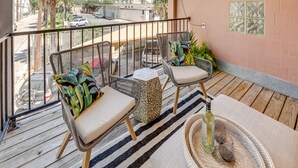 Un balcon avec des fauteuils en osier, un tapis tissé et une petite table.