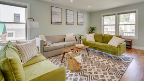 A living room with two green sofas, a patterned rug, and a large window.