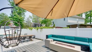 A deck with a beige sofa, a wooden table, and a hanging chair.