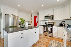 Una cocina moderna con armarios blancos, electrodomésticos de acero inoxidable y una isla central.