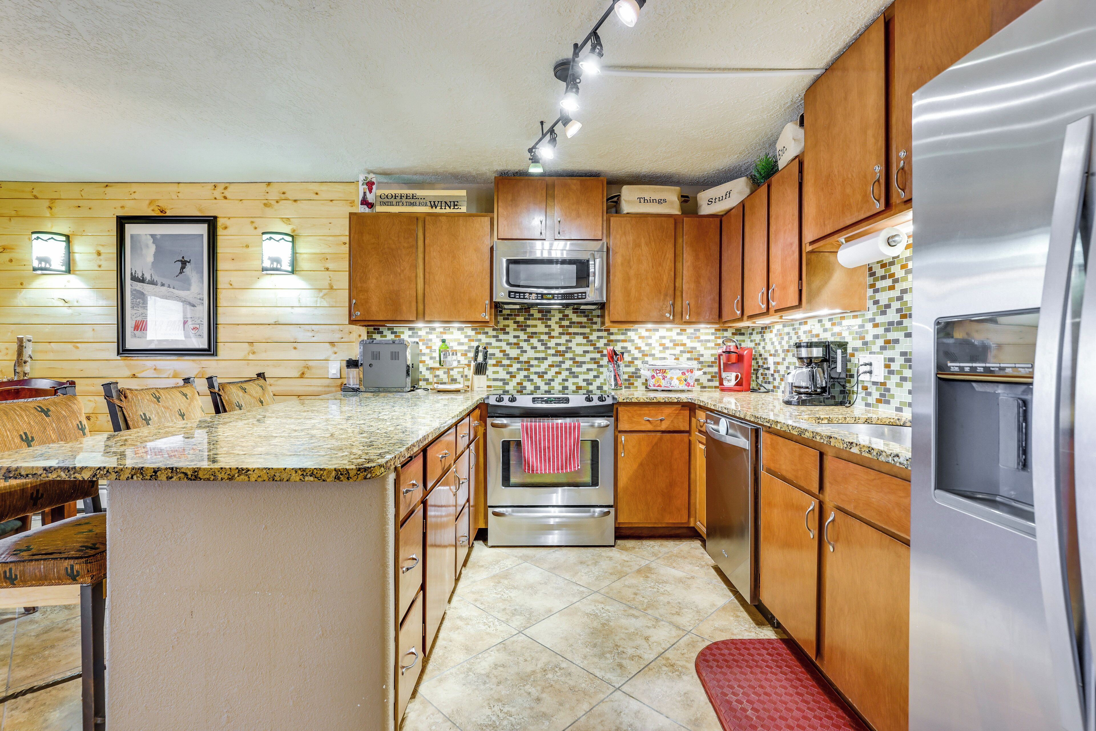 A kitchen with wooden cabinets, a stainless steel oven, a microwave, and a refrigerator.