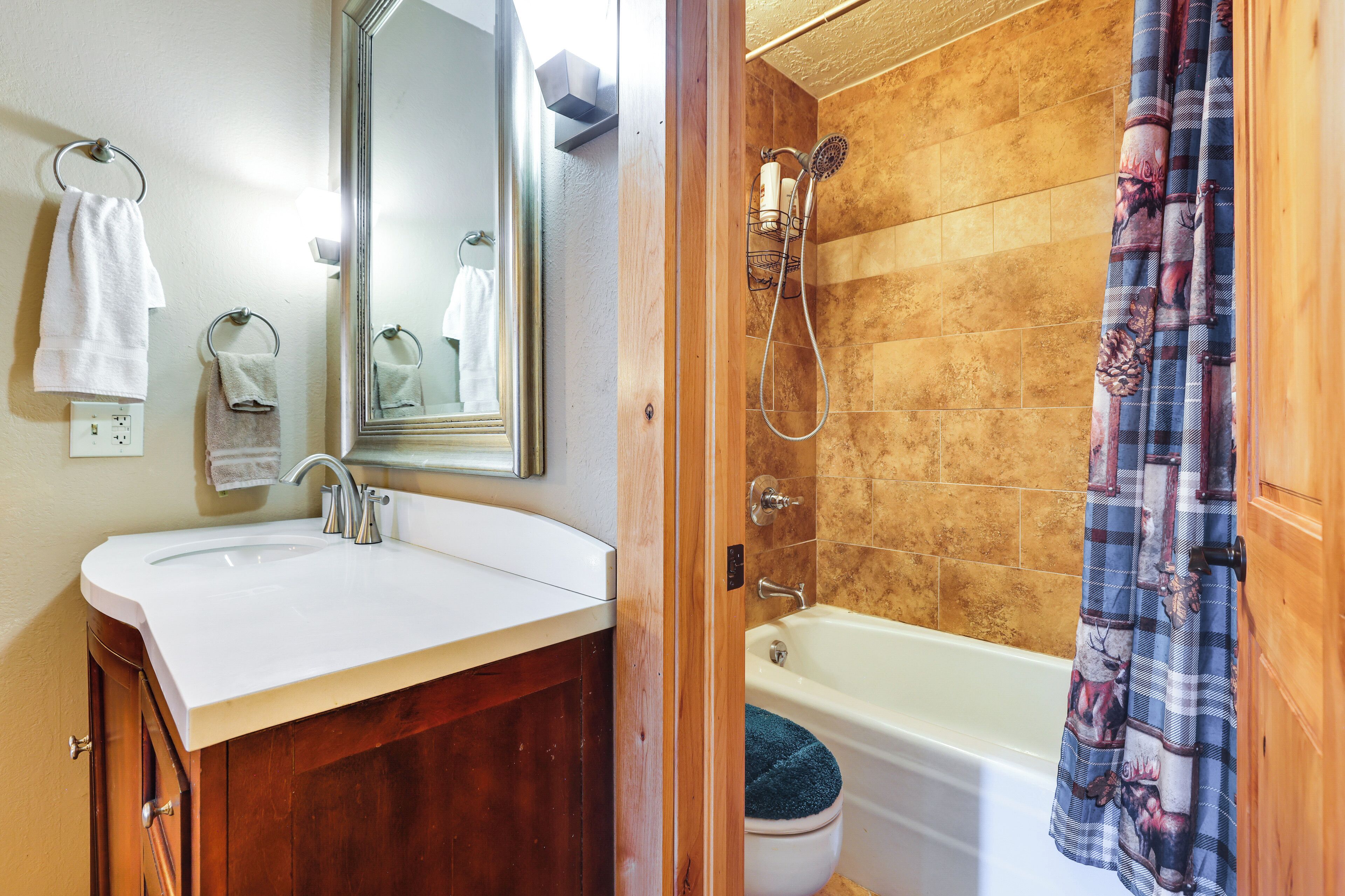 A bathroom with a white sink, wooden vanity, a mirror, a shower with a wooden door, and a blue shower curtain.