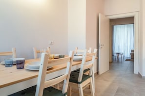 Un comedor con una mesa y sillas de madera, una mesita con una silla, y una puerta que da a otra habitación.
