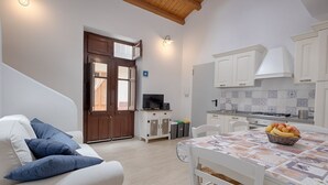 Una cocina moderna con armarios blancos, una mesa de comedor con mantel estampado y una cesta de frutas.
