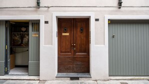 A building with a wooden double door, a grey garage door, and a small step leading to the entrance.