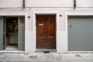 Un edificio con una puerta doble de madera, una puerta de garaje gris y un pequeño escalón que lleva a la entrada.