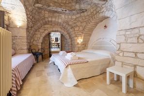 Une pièce aux murs de pierre, avec un lit, une chaise et une petite table.