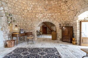 Une pièce aux murs de pierre, avec une table en bois rustique, un tapis à motifs et un meuble en bois.