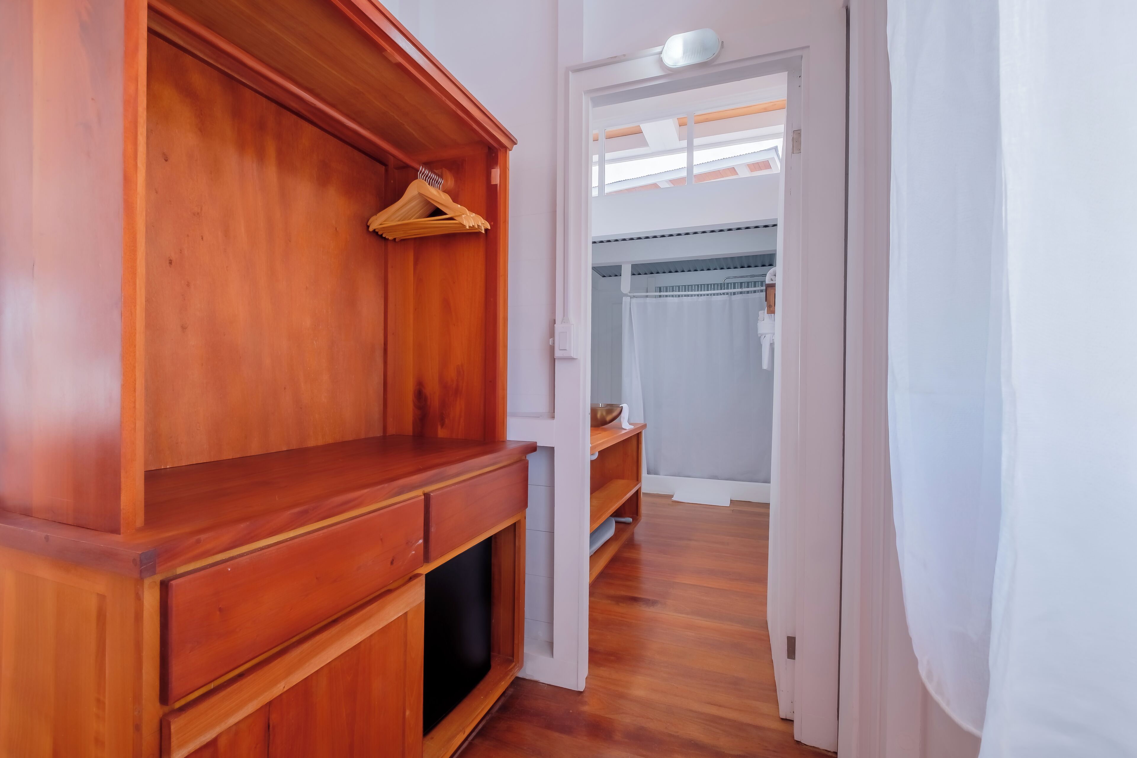 Ein Holzschrank mit Kleiderstange, Spiegel und Ablagefläche.