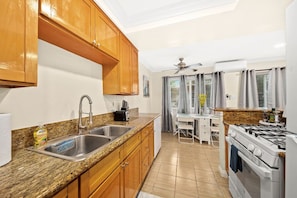 A kitchen with granite countertops, wooden cabinets, a stainless steel sink, a gas stove, and a ceiling fan. - Cozy & Serene ~ 12 mins to Downtown LA (Alhambra)