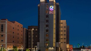 Un hotel de varios pisos con un logotipo destacado en la fachada, que presenta un diseño arquitectónico moderno con una combinación de elementos de vidrio y concreto.