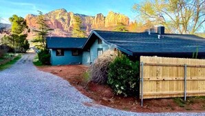 A two-story house with a gravel driveway, a wooden fence, and a mountain backdrop. - Quaint 1-bedroom Unit  w/ Hottub in Uptown Sedona (Sedona)