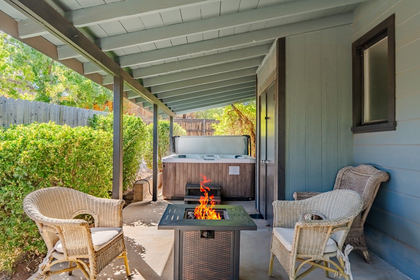 Un patio exterior con una chimenea, dos sillas de mimbre y un jacuzzi.