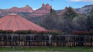 A house with a red roof, surrounded by a wooden fence and a garden with red flowers. - Quaint 1-bedroom Unit  w/ Hottub in Uptown Sedona (Sedona)