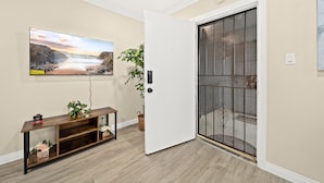Ein Zimmer mit einem Holzkonsolentisch, einer Topfpflanze und einer Tür mit einem Metallgitter.