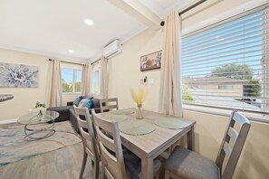 Una sala de estar moderna con comedor, que incluye un sofá, una mesa de centro de vidrio y una mesa de comedor con sillas.