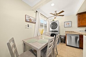 Une cuisine de taille réduite, dotée d’un ventilateur de plafond, d’un lave-linge et d’un lave-vaisselle.