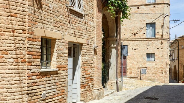 A narrow cobblestone street flanked by historic stone buildings with arched doorways and windows. - [Historic Center] A/C e WiFi in the Heart of Le Marche region (Lapedona)