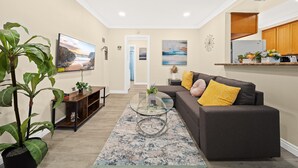 A modern living room with a grey sofa, a glass coffee table, and a large potted plant. - Cozy n Serene 12mins to Downtown LA (Alhambra)