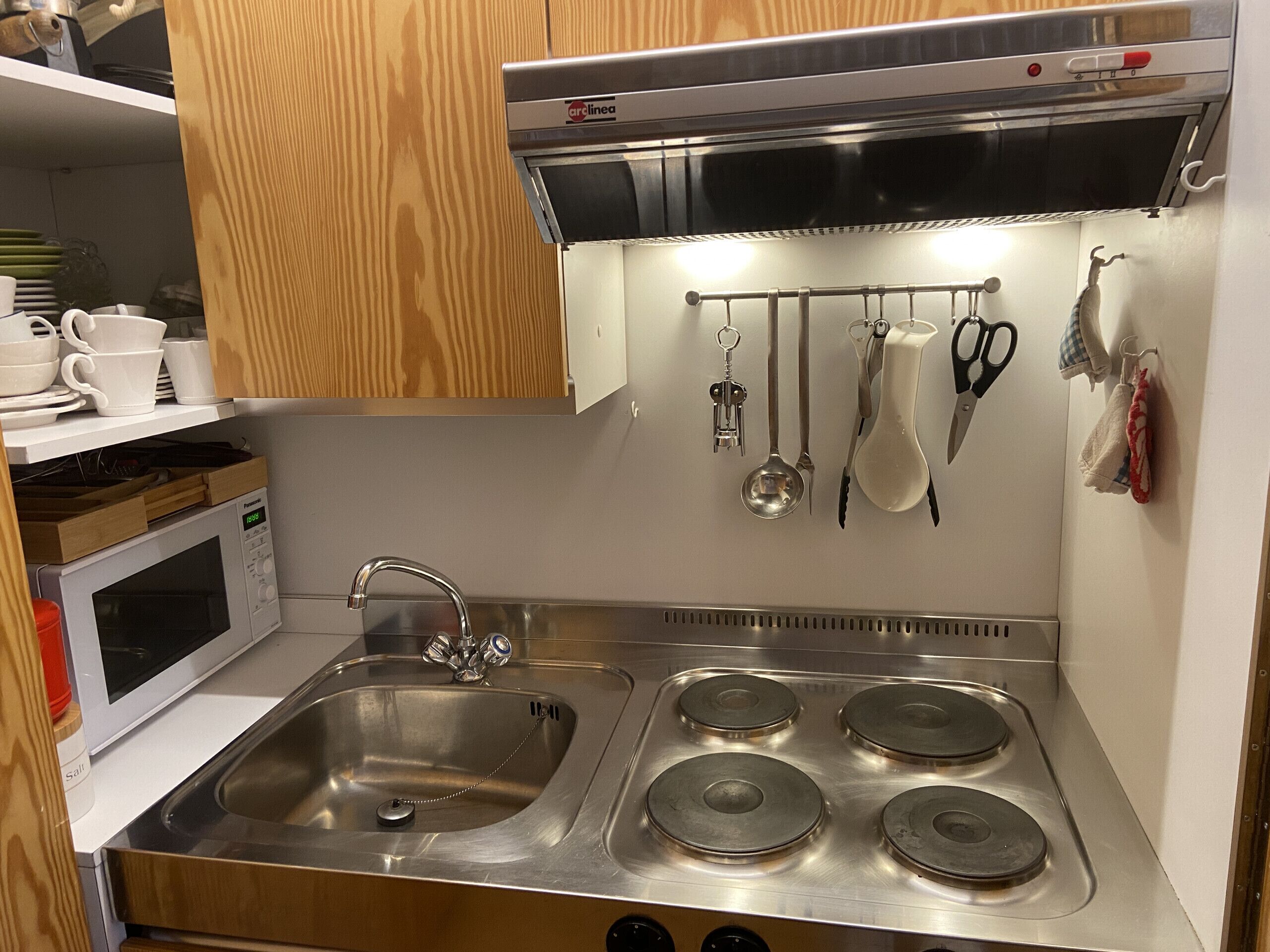 A stainless steel kitchen with a double sink, four burners, and a microwave.