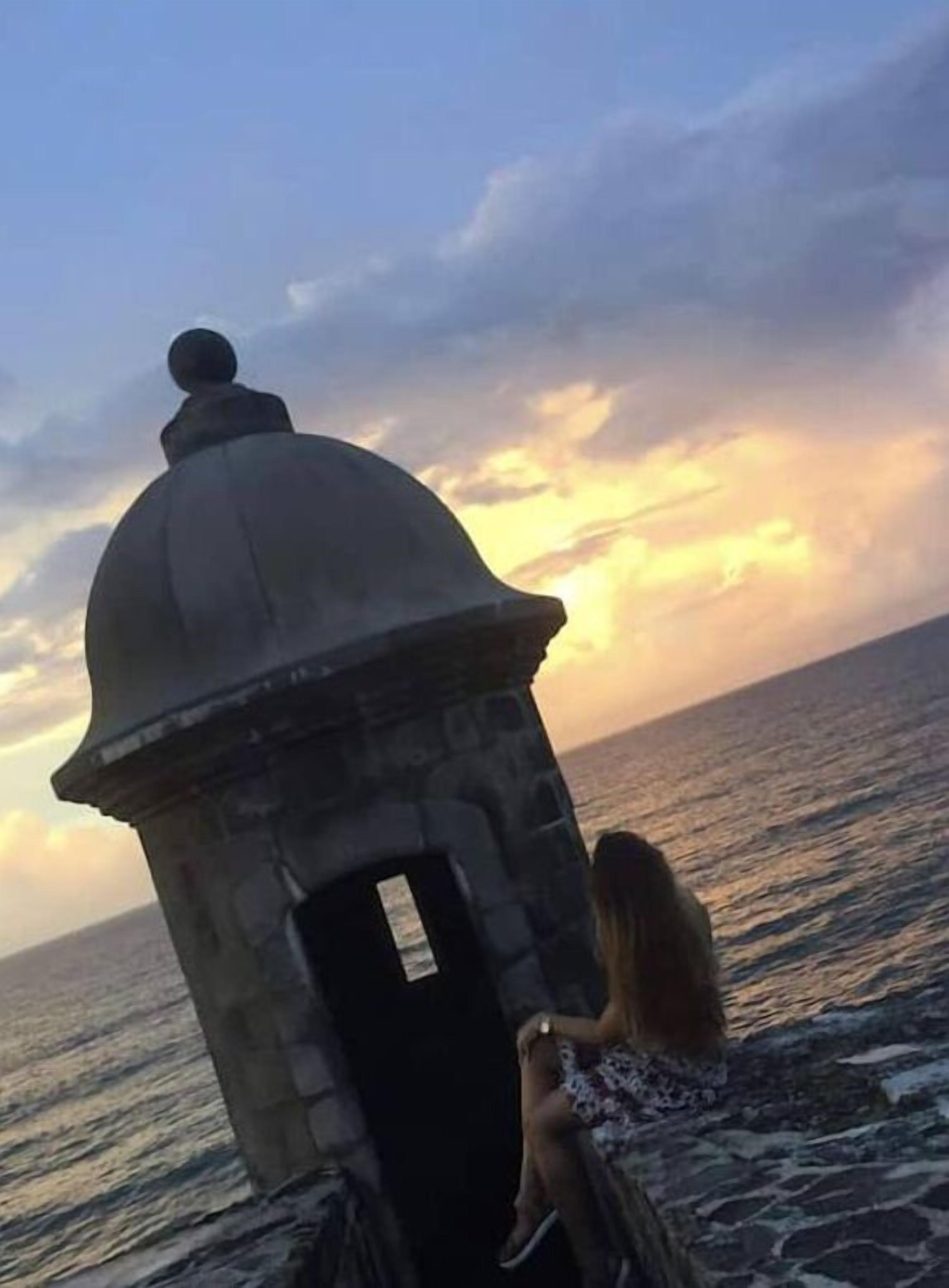 A stone structure with a dome, possibly a lighthouse, overlooking the sea at sunset.