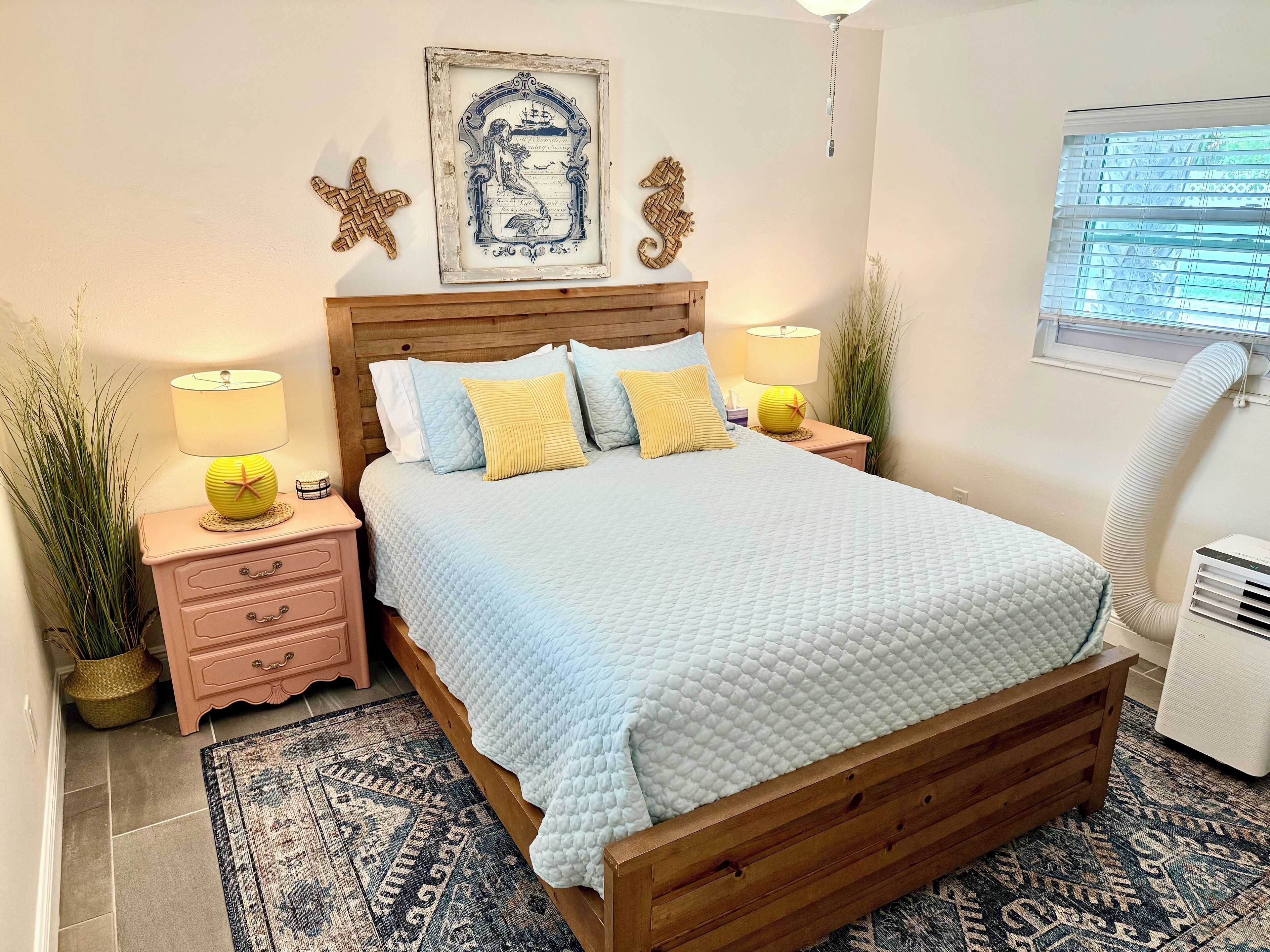 Une chambre à coucher avec un lit en bois, une couvre-lit matelassée bleue et deux tables de chevet avec des lampes.
