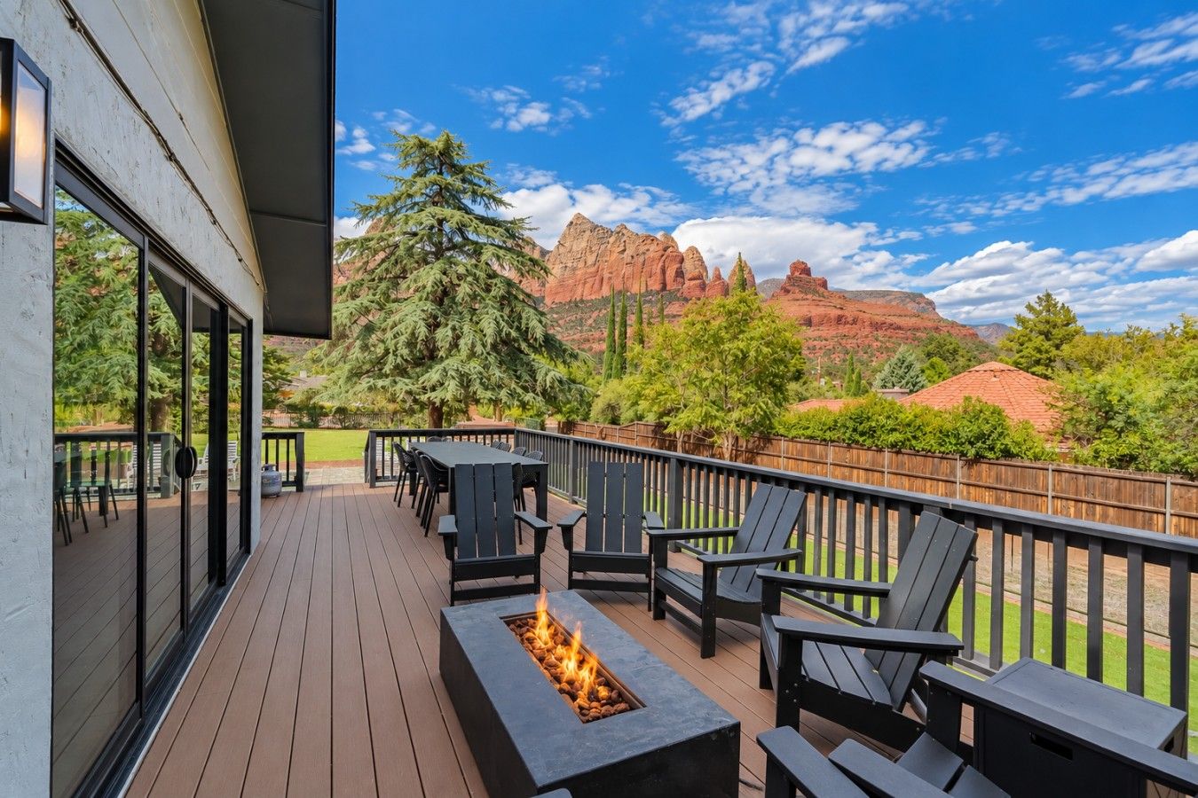 A deck with outdoor seating and a fire feature, overlooking a mountainous landscape.