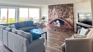 Een ruime woonkamer met een grote hoekbank, een open haard en een televisie.