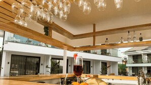 A wooden bar area with a glass of red wine, a fruit basket, and hanging wine glasses. - S-Cape Hotel Fethiye (Fethiye)