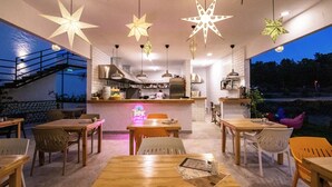 A restaurant with wooden tables and chairs, a neon sign, and star-shaped hanging lights. - S-Cape Hotel Fethiye (Fethiye)