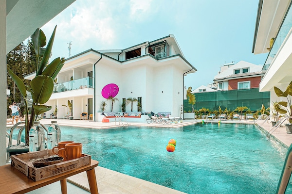 Una piscina al aire libre, sombrillas, sillones reclinables de piscina