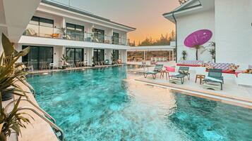 Una piscina al aire libre, sombrillas, tumbonas