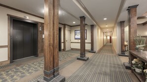 Un pasillo de hotel con pilares de madera, alfombra estampada y una puerta con un letrero.